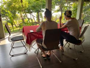 two women sitting at a table in a room at Lake Entrance in Ibbagomuwa