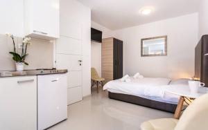 a bedroom with a bed and a table and a kitchen at Apartments Bernardeta 1 in Baška