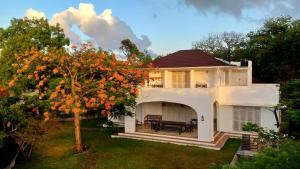 a white house with a tree in the yard at Villa Maridadi in Ukunda Airport