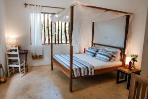a bedroom with a canopy bed with blue and white pillows at Villa Maridadi in Ukunda Airport
