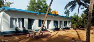 戈卡尔纳Bele Beach Front Inn的白色的房子,有蓝色的屋顶和两棵棕榈树