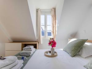 a bedroom with a bed with towels and a vase of flowers at Studio COSY in the heart of Paris - Mobility lease in Paris