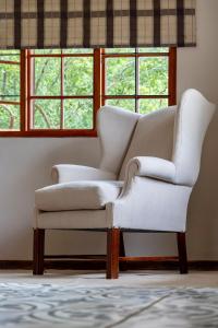 a white chair in a living room with windows at Ebernburg Cottage in Nottingham Road