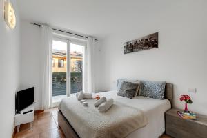 Un dormitorio con dos camas y un televisor y una ventana. en Residence Due Laghi - Happy Rentals, en Ispra