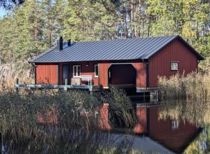 a red cabin on the water with trees in the background at Hus Upplångö in Figeholm