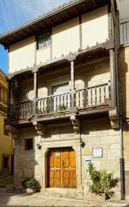 a building with a wooden door and a balcony at Antigua Posada, Valle del Jerte in Tornavacas