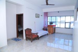 a bedroom with a bed and a chair and window at The Erumely Palace in Mundakāyam