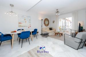 una sala de estar blanca con mesa y sillas azules en Palm Beach Apartment, en La Herradura