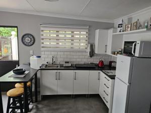 a kitchen with white cabinets and a white refrigerator at Giraffe's Rest, Self Catering Studio Apartment in White River