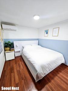 a bedroom with a white bed with a blue wall at Seoul Nest in Seoul