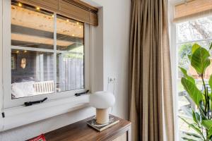 a living room with a window and a table with a lamp at Welkom in ons huisje in het bos met prive sauna in Lunteren