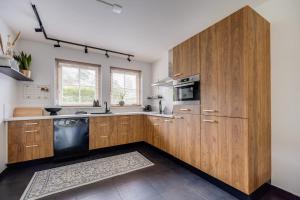 a kitchen with wooden cabinets and a black dishwasher at Welkom in ons huisje in het bos met prive sauna in Lunteren +46 photos