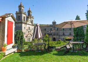 a garden with two tables and an umbrella in front of a castle at Pension A Casiña D,avoa Oseira in Osera