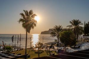 a beach with a palm tree and the sun setting at AQI Hydros Club in Kemer