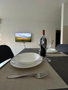 una mesa con un plato blanco y una botella de vino en Urban Sky Loft Fiumicino, en Fiumicino