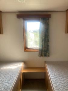 a small room with two beds and a window at Leuk chalet op de Veluwe in Epe
