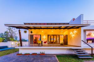 a modern house with a patio and a backyard at SaffronStays Blue Jasmine in Nashik