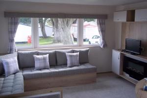 a living room with a couch in front of a window at Get-a-Wey a static caravan at Haven Weymouth Bay in Preston