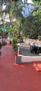 Rock View Palace Lighthouse Beach Resort في تريفاندروم: حديقة بها طاولات وكراسي وأشجار نخيل