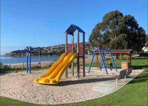 a playground with a yellow slide in a park at Blackmans Bay Villa in Kingston Beach