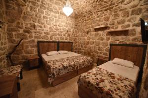 a bedroom with two beds and a stone wall at Artuklu Kervansaray Hotel in Mardin
