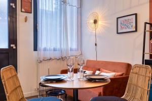a table and chairs with wine glasses and a couch at Déborah studio calme lit et place de parking in Rouen