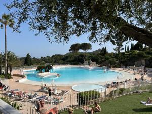 a large swimming pool with people sitting around it at Appartement 4 personnes Cap Estérel centre du village in Saint-Raphaël