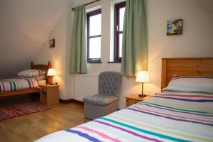 a bedroom with a bed and a chair and two windows at Tan-yr-Onnen Llangrannog in New Quay