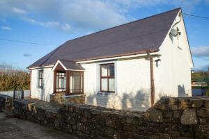 a small white house with a stone wall at Tan-yr-Onnen Llangrannog in New Quay