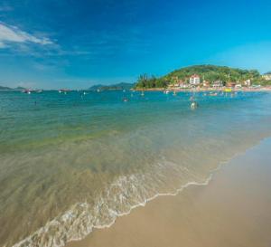 a beach with a group of people in the water at Recanto da Magia in Palhoça