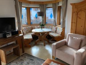 een woonkamer met een tafel en stoelen en een televisie bij Haus am Wiesbach in Reit im Winkl
