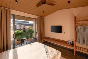 a bedroom with a bed and a tv and a balcony at Olala Glamping Bảo Lộc in Bao Loc