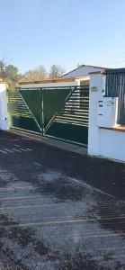 a green gate in a parking lot next to a building at Studio plein Sud au calme in Montauban