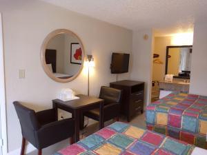 a hotel room with a desk and a bed and a mirror at Red Carpet Inn Airport Fort Lauderdale in Fort Lauderdale