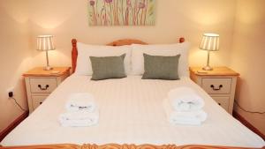 a bedroom with a large white bed with two lamps at 3 Bed Cottage - Parking - Ideal for Work Trips in Swansea