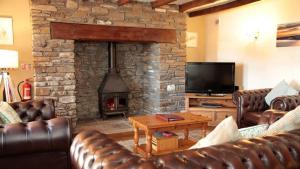 a living room with leather couches and a stone fireplace at 3 Bed Cottage - Parking - Ideal for Work Trips in Swansea