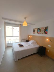 a bedroom with a white bed and a large window at Apartamentos Marina Suites in Grao de Castellón
