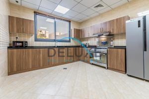 a kitchen with wooden cabinets and a white refrigerator at Special Rate with Temp Controlled Pool, BBQ & Maid's by Deluxe Holiday Homes in Fujairah