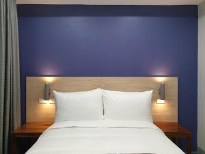 a bed with white pillows and a purple wall at Leez Inn Makati in Manila