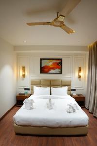 Un dormitorio con una cama blanca con ventilador de techo. en The Royal Velvet Hotel & Resort, en Rohtak
