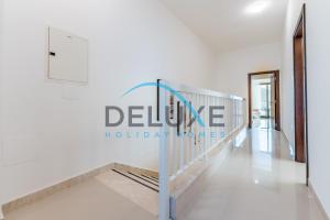 a white hallway with a sign that reads deluce holiday homes at Special Rate with Temp Controlled Pool, BBQ & Maid's by Deluxe Holiday Homes in Fujairah