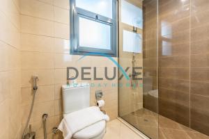 a bathroom with a toilet and a window and a shower at Special Rate with Temp Controlled Pool, BBQ & Maid's by Deluxe Holiday Homes in Fujairah