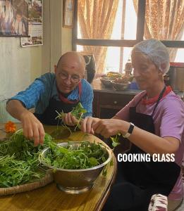Un uomo e una donna che preparano i green su un tavolo di Jhigu Homestay Patan a Kathmandu