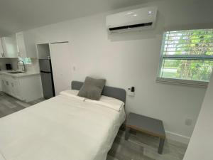 a small white bedroom with a bed and a window at Newly renovated studio close to the beach in Hollywood