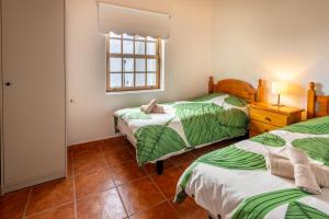 a bedroom with two beds with green and white sheets at Casa de Los Establos - Finca Camacho in Santa Cruz de la Palma