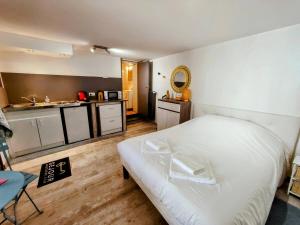 Un dormitorio con una cama blanca y una cocina. en République - Séjour à Auxerre, en Auxerre