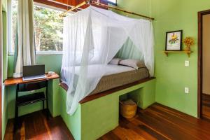 a bed in a room with a desk and a laptop at Casa da Floresta Aruá, Praia do Forte, Bahia in Mata de Sao Joao