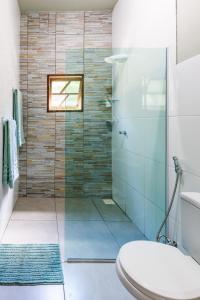 a bathroom with a glass shower with a toilet at Casa da Floresta Aruá, Praia do Forte, Bahia in Mata de Sao Joao