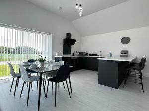 a kitchen and dining room with a table and chairs at Rose - Luxury New Holiday Hot tub lodge in Ospringe