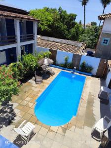 uma grande piscina com duas cadeiras de jardim ao lado de uma casa em Pousada Flor do Dendê em Arraial d'Ajuda